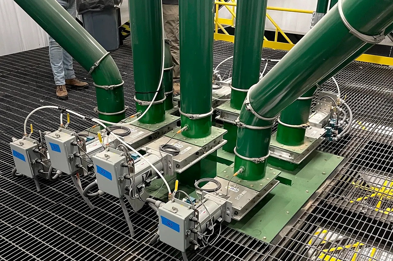 Batería de válvulas de compuerta Roller Gate de Vortex instaladas en tuberías verdes de alimentación por gravedad para granos de café en una planta de tostión.