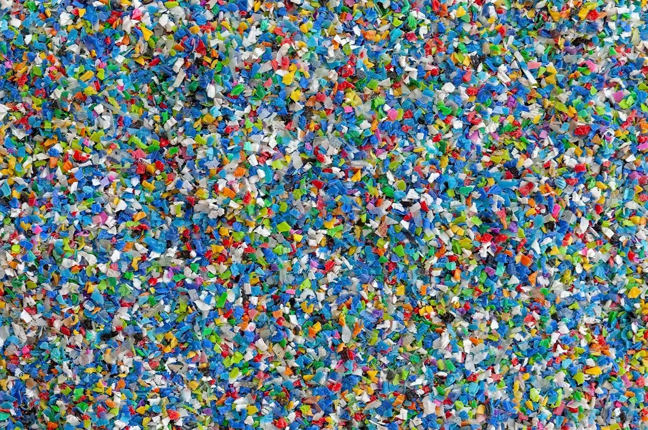 Acumulación de partículas de plástico triturado de diferentes colores, que ilustra la variedad de granulometría y formas en los materiales sólidos a granel.